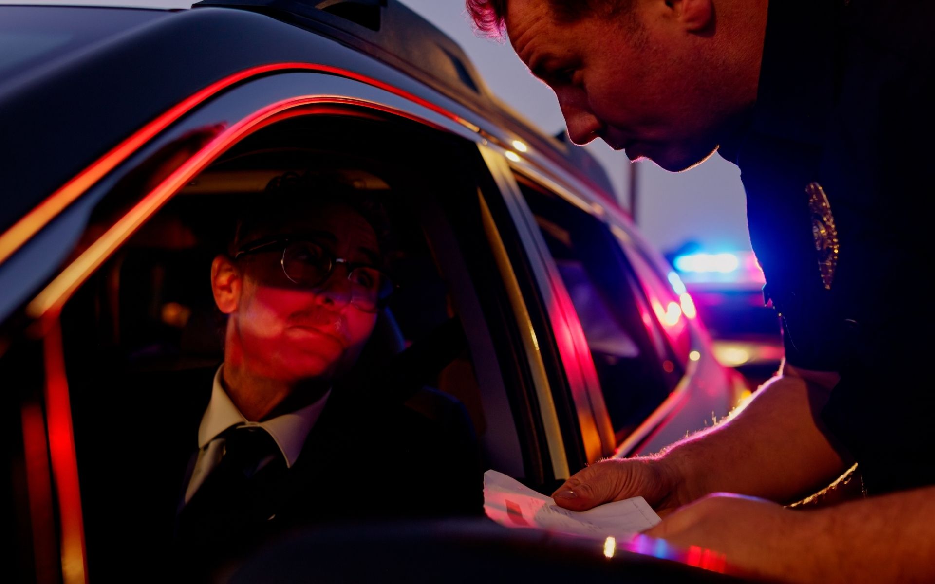 Agente junto a la ventanilla de un vehículo durante una parada de tráfico nocturna