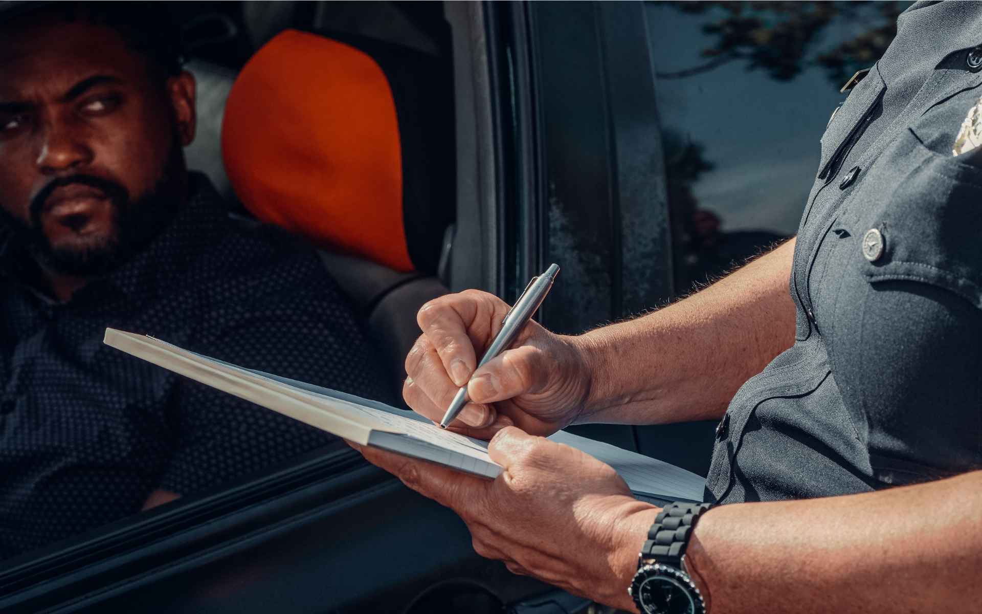 Agente escribiendo en un portapapeles junto a un conductor dentro de su vehículo